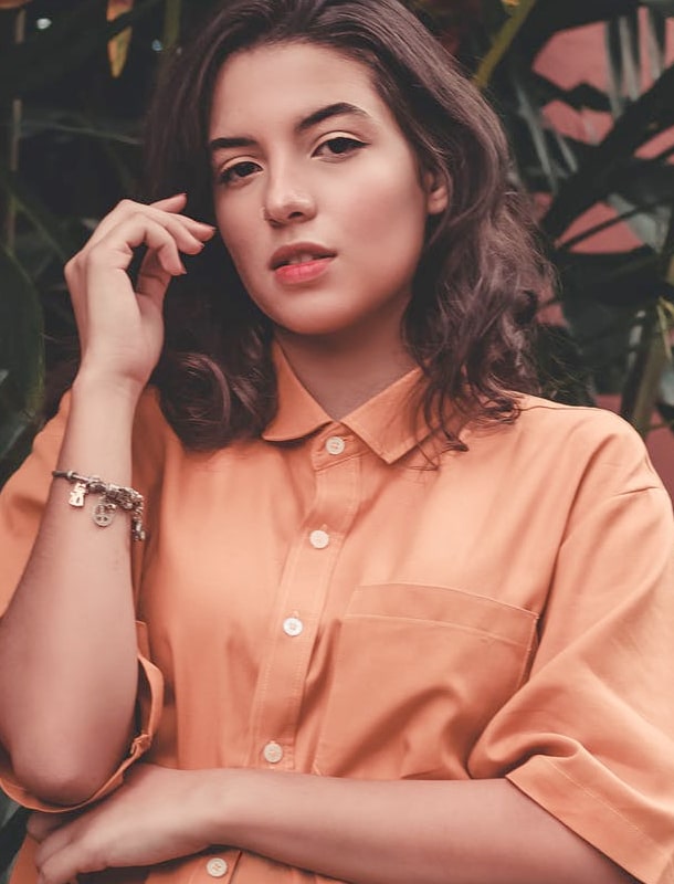 Woman with brown hair in orange shirt